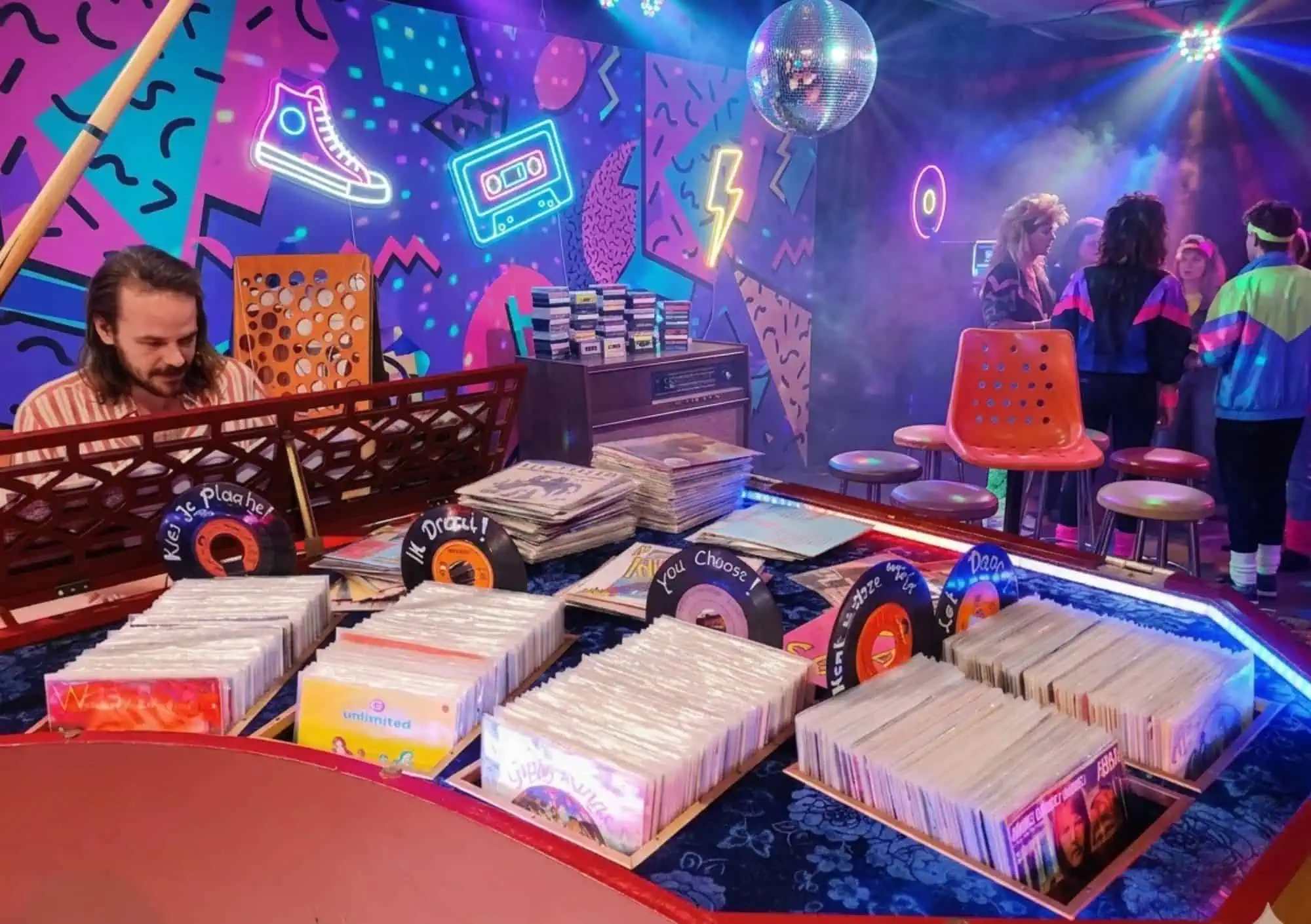 Totaaloverzicht van een Back to the Eighties bedrijfsfeest met filmauto's en decoratie